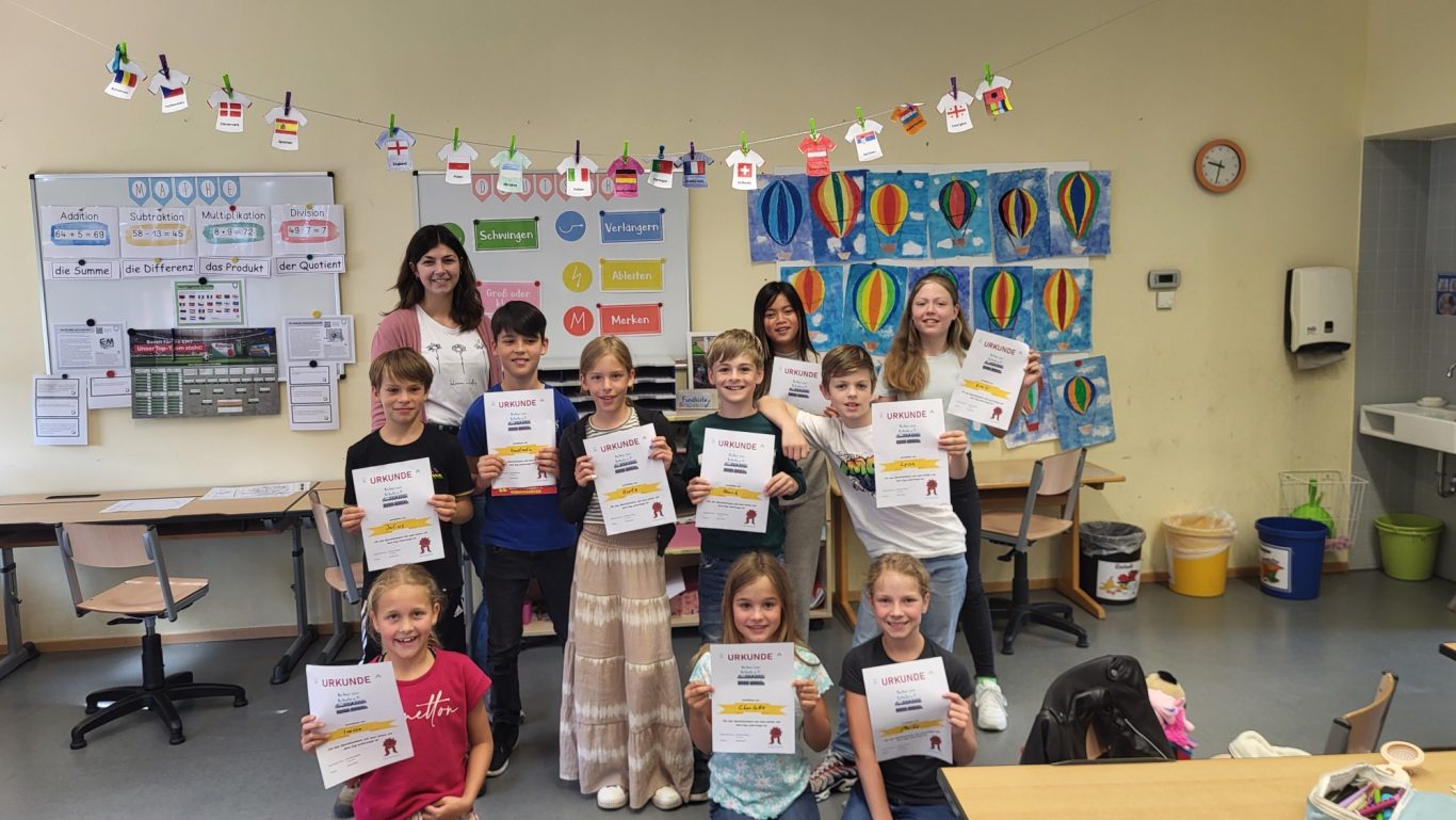 Eine Gruppe von Kindern hält stolz Zertifikate in einem Klassenraum.
