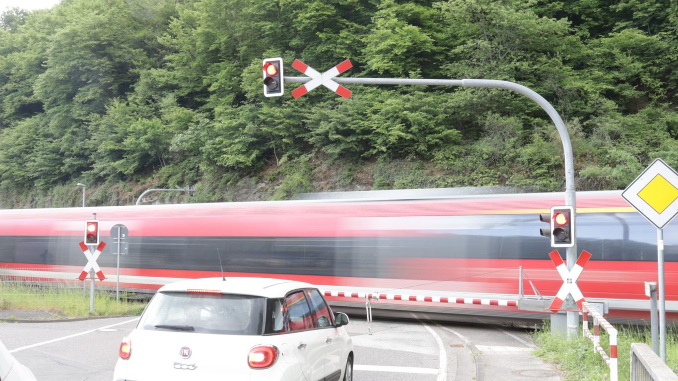 Vorbeifahrender Zug Roter Zug fährt an einer Straßenkreuzung mit Andreaskreuz und Ampel vorbei.